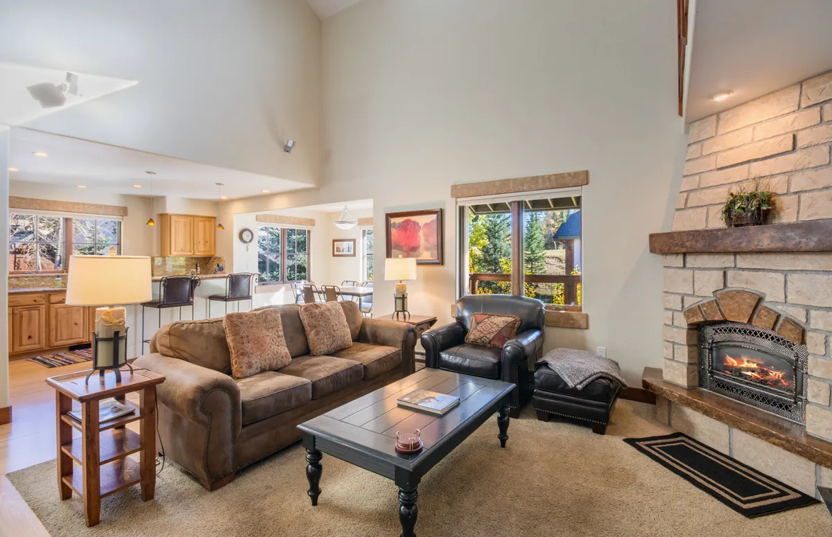 A pleasant living area with a sofa set before a fireplace and dining space, framed by windows that offer captivating views of nature. The room is designed for relaxation but also provides a quiet, inspiring environment for remote work.